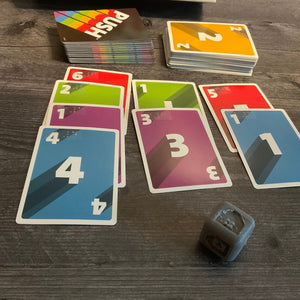 Another shot of the cards. The die is closer to the camera and has the color green showing on it indicated by a braille g