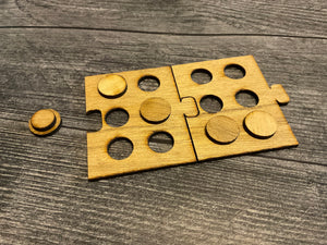A close up of 2 wooden braille puzzle pieces put together. Pegs are fit into the pieces spelling out e and a dash for some reason that I can't remeber.