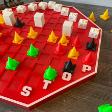 Load image into Gallery viewer, A picture of the other side of the board showing the pawns of different colors. Red has circles, yellow has triangles, black has xs and green has pentagons.
