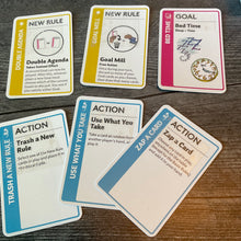 Load image into Gallery viewer, A close up on some rule cards, a goal card and some action cards. The action cards have their function embossed on them in braille.
