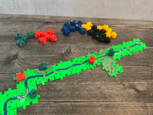 A wide shot showing the river with various meeples on it. The replacement pieces of all the colors can be seen in the background.