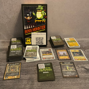 A shot showing all the various types of cards in boss monster, dungeon, hero, boss and spell cards. The cards have QR codes on the back and transparent braille on the front. Some of the cards also have braille on the back to help sort