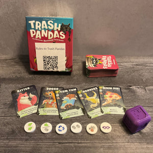 Trash pandas box with 5 cards in front of it. Kitten, doggo, yum yum, nanners and mmm pie. The tokens and cards have transparent braille on them. A huge 3d printed die is also shown