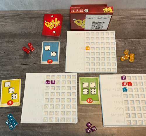 The game is shown setup(red version). There are trays next to the cards to sort who's dice are who's. The cards all have transparent braille on them indicated the needed dice and their point value