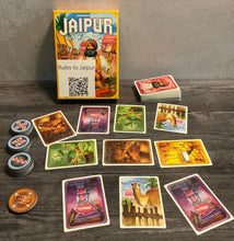 Load image into Gallery viewer, The game Jaipur laid out with a market in the middle between two players. The different favor tokens are shown to the left, with braille on both sides of the tokens
