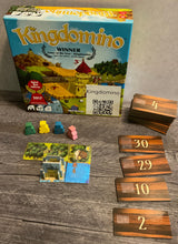 Load image into Gallery viewer, The game box, with the meeples in front of it. One 3d castle is setup and the dominos are labeled on both sides in transparent braille
