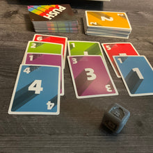 Load image into Gallery viewer, Another shot of the cards. The die is closer to the camera and has the color green showing on it indicated by a braille g
