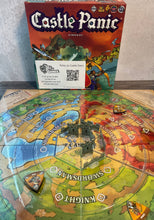 Load image into Gallery viewer, A shot of the game and the board with the castle setup in the center. The board has a clear plastic overlay on it.
