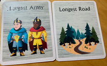 Load image into Gallery viewer, Close up on largest army and longest road cards. They are both print and braille in full color on hard plastic.
