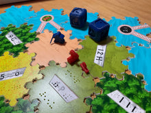 Load image into Gallery viewer, Close up on dice and robber. The robber is a meeple with a cane. The 3  for 1 port is facing the wrong direction because Richard was too hasty when setting up the photo and wasn&#39;t paying attention.
