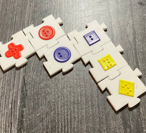 Close up on linked acrylic pieces. Tactile shapes are on all of the tiles and they fit together like jigsaw pieces. Braille is on the tactile shapes to tell the user the color.