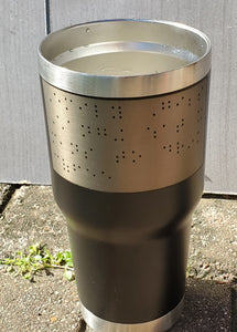 Black metal cup with rectangular portion etched out, leaving a silver rectangle with black braille dots. Can be seen by sighted individuals in addition to it being tactile