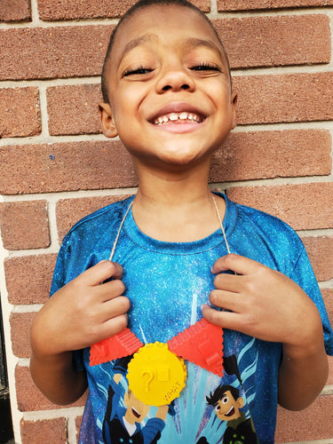 A boy with a big smile wearing the core beads as a necklace